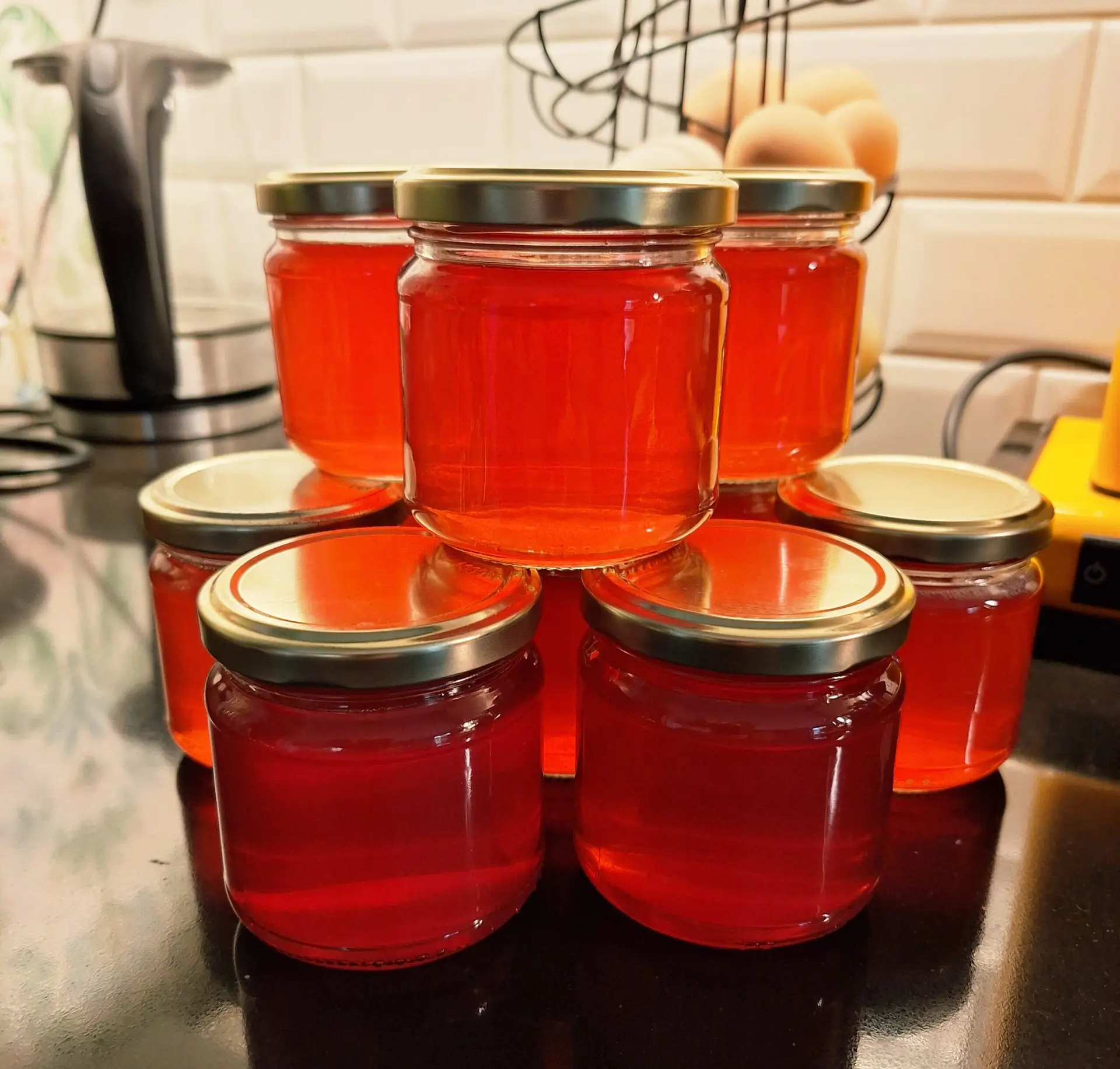 Glasburkar fyllda med röd hemkokt gelé staplade på köksbänk